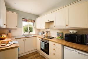 a kitchen with white cabinets and a black microwave at Crailing West Lodge in Jedburgh