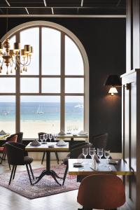 uma sala de jantar com mesas e vista para a praia em Grand Hôtel Perros-Guirec em Perros-Guirec