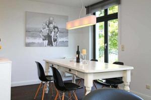 a dining room with a white table and black chairs at Villa Schering App 4 Black White in Heringsdorf