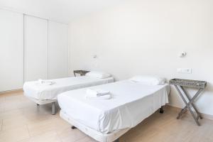 Apartamentos La Rosita Old Town B-21 في بنيدورم: سريرين في غرفة بجدران بيضاء وأرضية خشبية