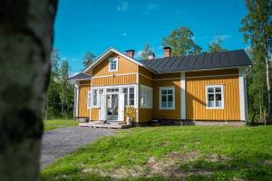 a small yellow house with a black roof at Unique loghouse and wood heated sauna in Ii in Ii
