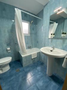 een blauw betegelde badkamer met een wastafel en een toilet bij Casa Pepe La Rosa in Tolox