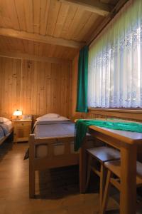 ブコビナ・タトシャンスカにあるGościniec u Marzenyのベッド、テーブル、窓が備わる客室です。