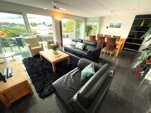 a living room with a black leather couch and a table at Vakantiehuis met eigen aanlegsteiger in Kortgene