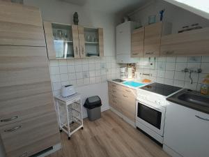 a small kitchen with white appliances and wooden cabinets at Ferienwohnung kleine Möwe mit E-Bike Verleih in Wilhelmshaven