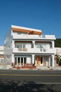 a white building with benches in front of a street at Seashore My Home in Eluan