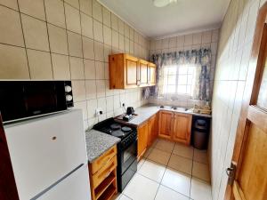 a small kitchen with wooden cabinets and a stove at Resthaven Guesthouse in Matatiele