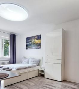 a white bedroom with a bed and a white cabinet at MsApartment Stylish wohnen in STUTTGART in Stuttgart