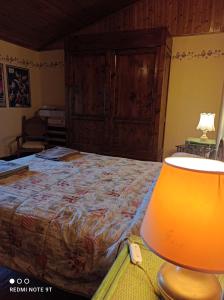 een slaapkamer met een bed en een tafel met een lamp bij Accogliente casa in pietra in borgo medievale in Serra Pistoiese