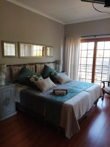 a bedroom with a large bed with a large window at Aan die Voet van die Magalies in Pretoria