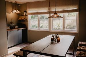 a kitchen with a wooden table and two windows at Stiftsgården Tallnäs in Skillingaryd