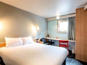 um quarto de hotel com uma cama, uma secretária e uma mesa em ibis Bourges Centre em Bourges
