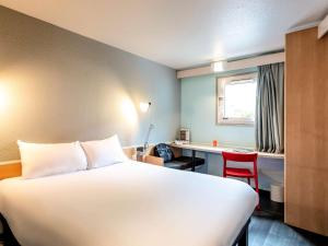 Cette chambre comprend un lit, un bureau et une table. dans l'établissement ibis Bourges Centre, à Bourges