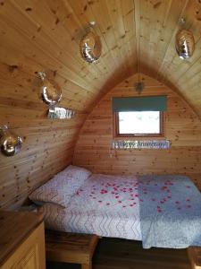 Sunny Mount Glamping Pod في Long Marton: غرفة نوم بسرير في كابينة خشبية