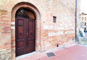 a brick wall with a wooden door on a building at Torre Salvucci Maggiore Medieval Tower Experience in San Gimignano
