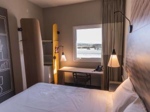 a bedroom with a bed and a desk and a window at Ibis Lorena - Circuito da Fé in Lorena