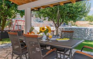 a dining table and chairs on a patio with a swing at Cozy Home In Runovic With Outdoor Swimming Pool in Runović