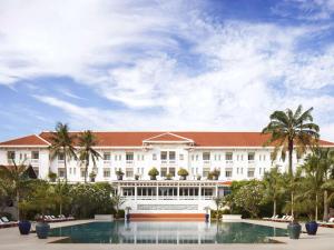 um grande edifício branco com uma piscina em frente em Raffles Grand Hotel d'Angkor em Siem Reap