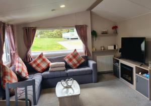 a living room with a couch and a television at Woodside Hot Tub Retreat in Newton on the Moor