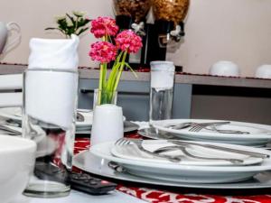 a table with plates and glasses and pink flowers on it at Morning flair Bed and Breakfast in Bloemfontein