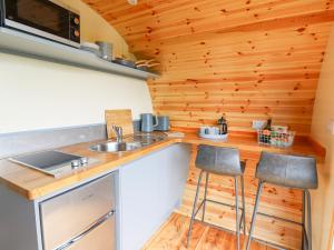 a kitchen with a sink and stools in a tiny house at Beacon View Pod in Knighton