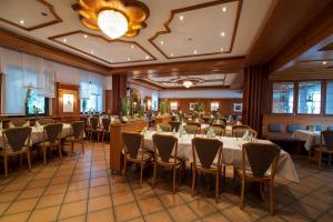 a banquet hall with tables and chairs and a chandelier at Landhotel Seerose in Langenzenn