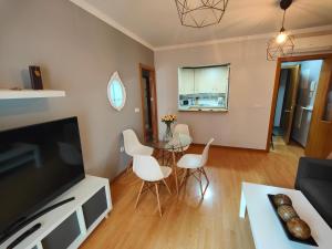 ein Wohnzimmer mit einem TV, einem Tisch und Stühlen in der Unterkunft GRAN ATICO en EL CENTRO CERCA DE LA PLAYA in Fuengirola