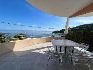 un tavolo e sedie su un balcone con vista sull'oceano di Harbour View - Oceanis Apartments a Póros