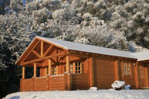 a log cabin with snow on the roof at BCC Loch Ness Log Cabins in Bearnock