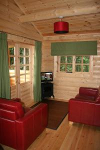 a living room with two red chairs and a television at BCC Loch Ness Log Cabins in Bearnock