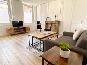 een woonkamer met een bank en een tafel bij * Le Droma D’or * Appartement Confort * Centre-ville in Calais