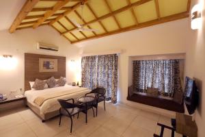 a bedroom with a bed and chairs and a television at Hummingbird Resort in Mount Ābu