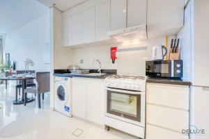 a kitchen with a stove and a dishwasher at Intimate Studio in Damac Ghalia Jumeirah Village Circle by Deluxe Holiday Homes in Dubai