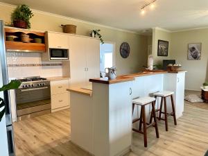 a kitchen with white cabinets and a counter with stools at Yorks View in Kingscote