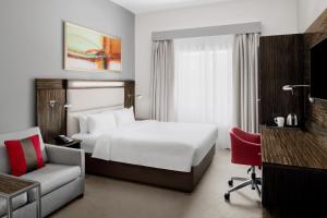 um quarto de hotel com uma cama branca e uma cadeira em Holiday Inn Express Dubai Internet City by IHG no Dubai