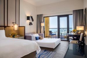 a hotel room with two beds and a desk at Amwaj Rotana, Jumeirah Beach - Dubai in Dubai