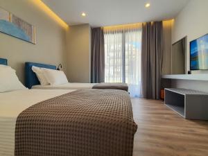 Habitación de hotel con 2 camas y TV en LOOKOUT Apartments, en Sarandë