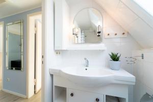a white bathroom with a sink and a mirror at Haus Sonnenberg in Timmendorfer Strand