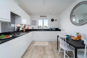 a kitchen with white cabinets and a table and a mirror at Blue Water in St Ives
