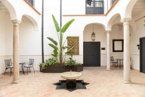 a courtyard with a potted plant and tables and chairs at Palacete Molina in Seville