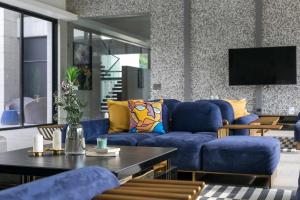 a living room with a blue couch and a table at Colossus by StayVista - Riverside luxury villa in Khalapur with a Spacious pool, Sauna, Private theater, Gazebo & Lawn in Lonavala