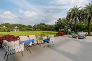 a patio with several chairs and a table with candles at Colossus by StayVista - Riverside luxury villa in Khalapur with a Spacious pool, Sauna, Private theater, Gazebo & Lawn in Lonavala