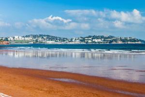 a view of the beach with a city in the background at Stylish 2 bed Paignton apartment, 5 minute walk to beach in Paignton