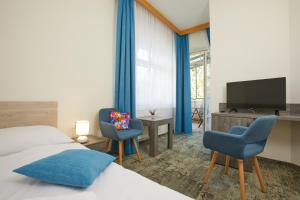 a bedroom with a bed and two chairs and a television at Penzion Vila Tereza in Hranice