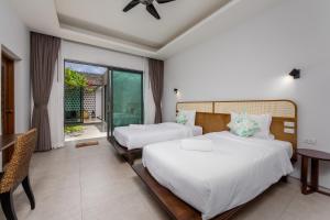 - une chambre avec 2 lits, une table et une fenêtre dans l'établissement Radi Villa x GoldStar, à Bang Tao Beach