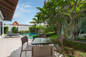 d'une terrasse avec une table et des chaises à côté de la piscine. dans l'établissement Radi Villa x GoldStar, à Bang Tao Beach