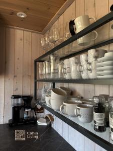 a shelf with plates and cups and dishes on it at Modern New Large Cabin Ski in out Sjusjøen in Ringsaker