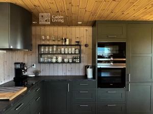 une cuisine avec des placards gris et un comptoir noir dans l'établissement Modern New Large Cabin Ski in out Sjusjøen, à Ringsaker