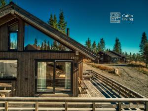 a house with glass doors on a wooden deck at New large cabin Ski in out Sjusjøen & sauna in Ringsaker