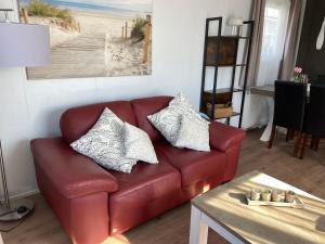 Chalet Oceanside Zeeland في سيروسكيرك: أريكة جلدية حمراء في غرفة معيشة مع طاولة